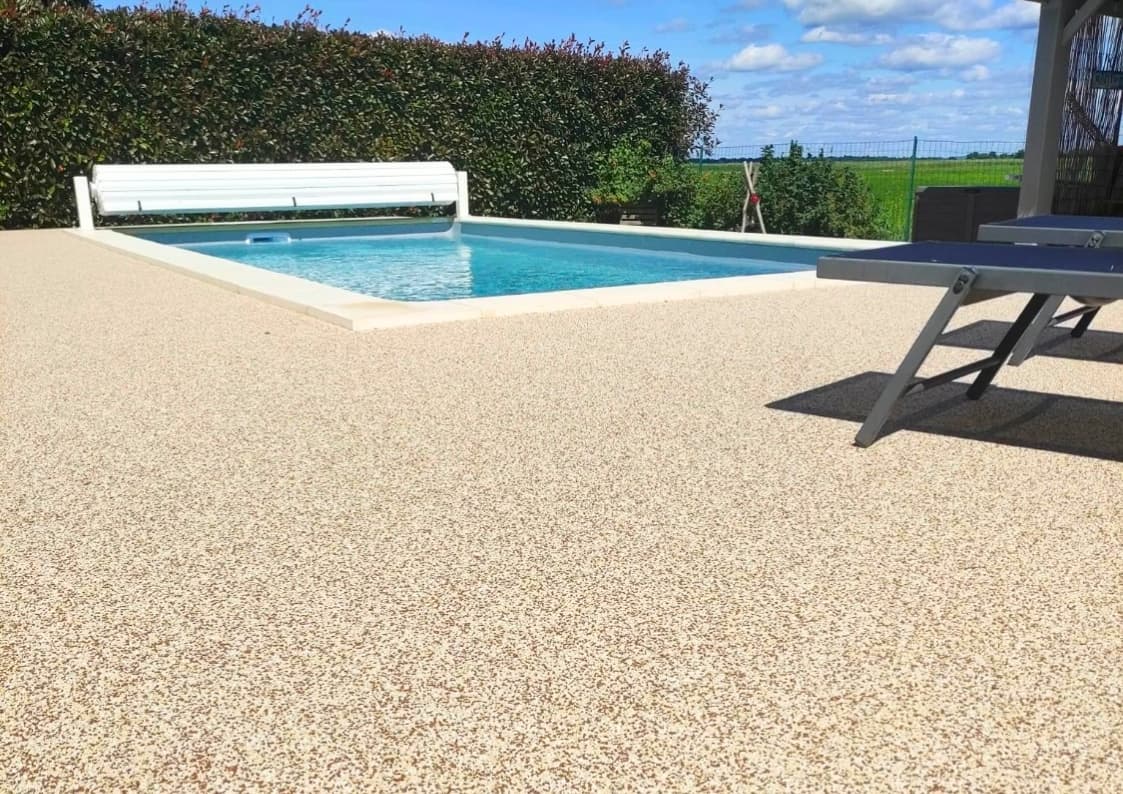 terrasse beige en résine à coté d'une piscine
